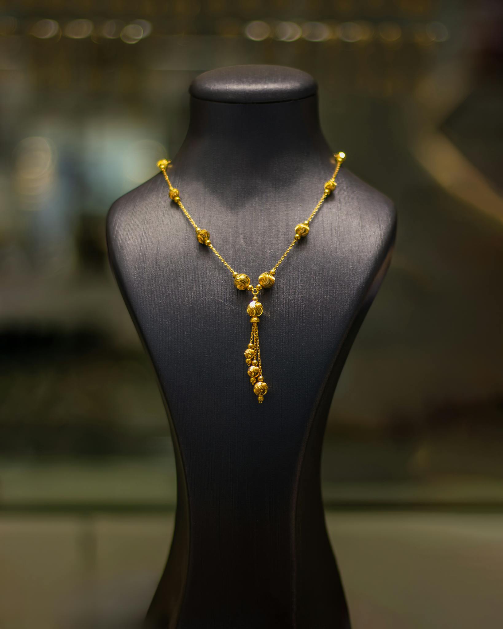 Luxurious gold necklace elegantly displayed on a black mannequin in a jewelry store.